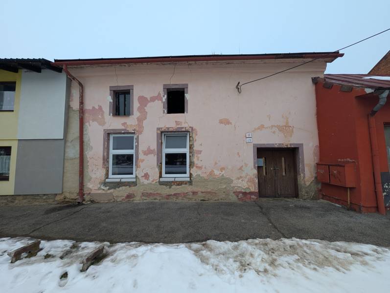 A family house on Remeselnícka Street in Ľubica with peeling plaster and a snow-covered sidewalk.