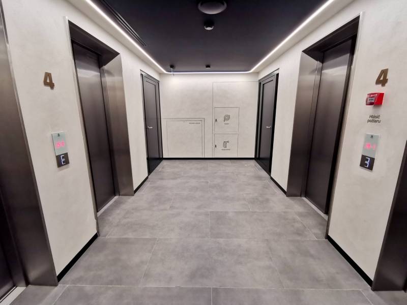 Elevator hall with four doors and a backlit ceiling in a 3-room apartment.