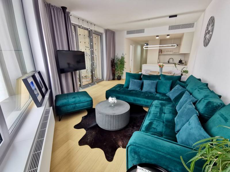 Living room of a three-room apartment with a turquoise sofa and a wooden decor floor.