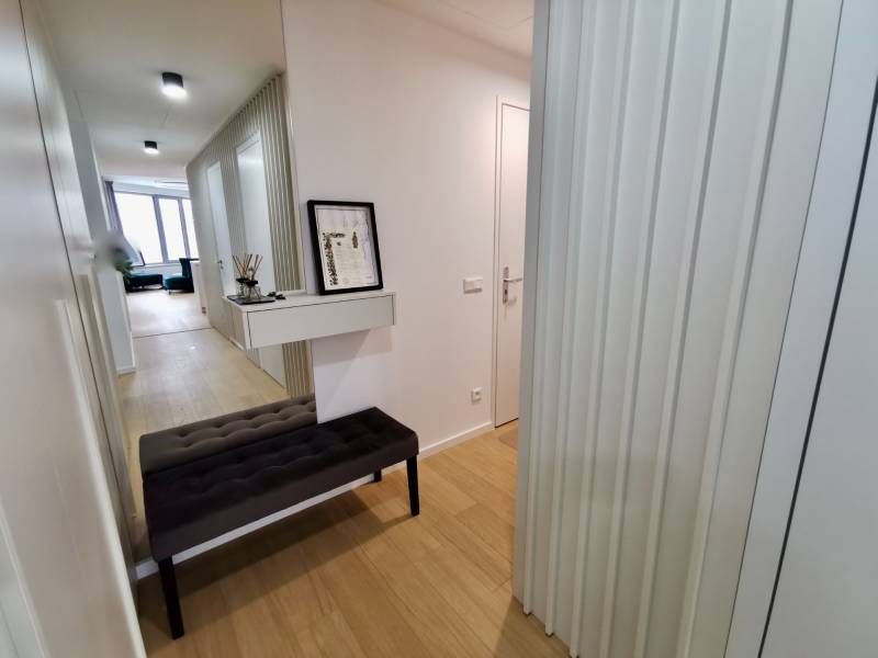Hallway of a 3-room apartment with a decorative table and wooden-patterned flooring.