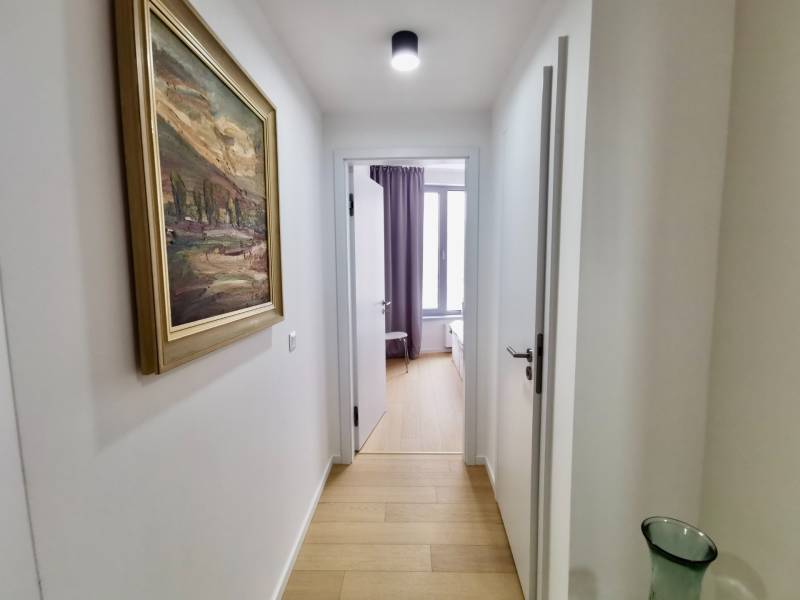 A hallway in a 3-room apartment with a wooden decor floor and a painting on the wall.