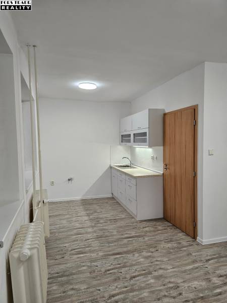 A kitchenette with white cabinets and a wooden decor floor in an office.