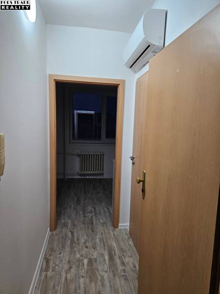 A narrow hallway in an office with a wooden decor floor and air conditioning.