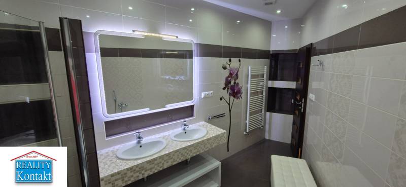A bathroom in a family house with two sinks, a large mirror, and a radiator.