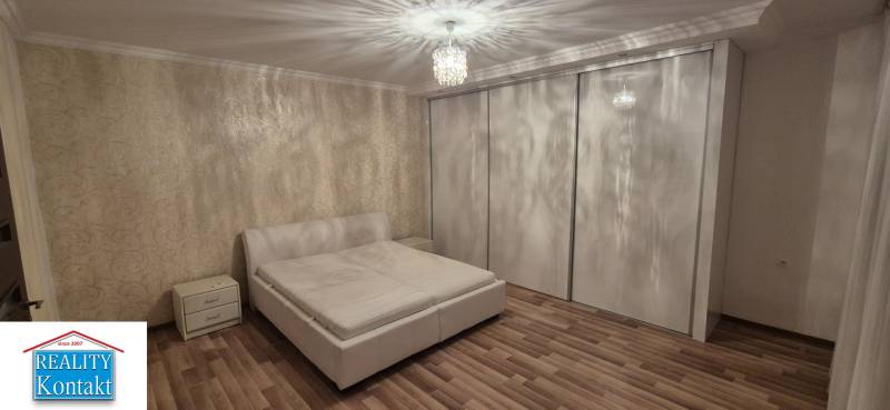 A bedroom in a family house with a large wardrobe, a bed, and a wooden decor floor.