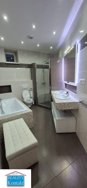 Bathroom in a family house with a bathtub, shower, two sinks, and a toilet.