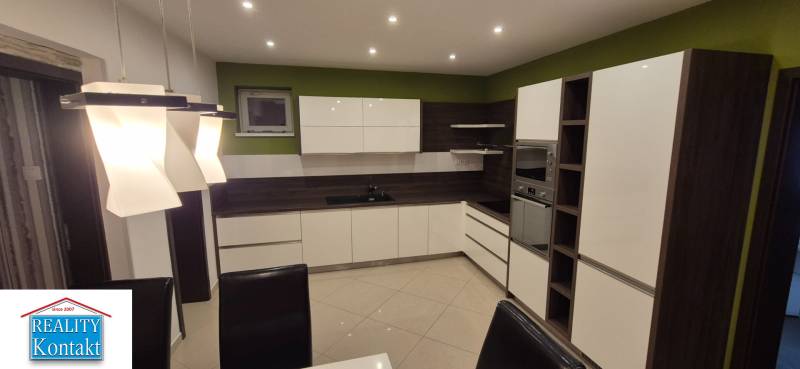 A kitchen in a family house with light fixtures, green walls, and built-in appliances.