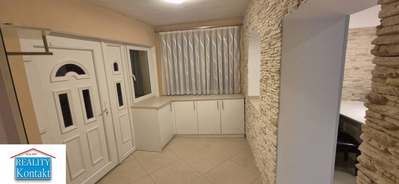 A white entrance hall in a family house with decorative stone and light tiles.