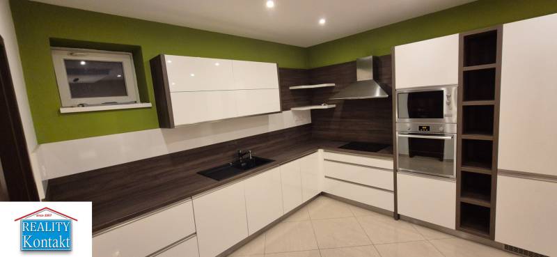 A kitchen in a family house with wooden decor and green walls.