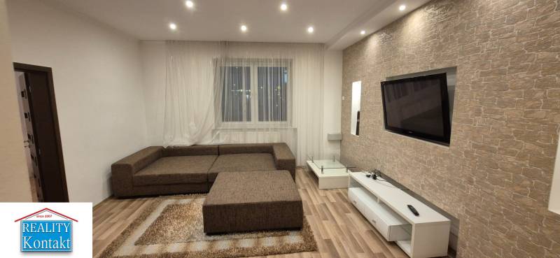 Living room with subtle stone cladding, a sofa, and a wooden decor floor in a family house.