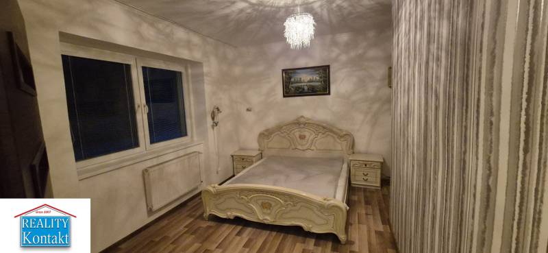 Bedroom in a family house with wooden floor decor, a bed, and a painting on the wall.