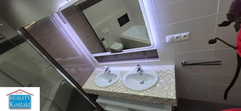 A bathroom in a family house with a double sink and an illuminated mirror.