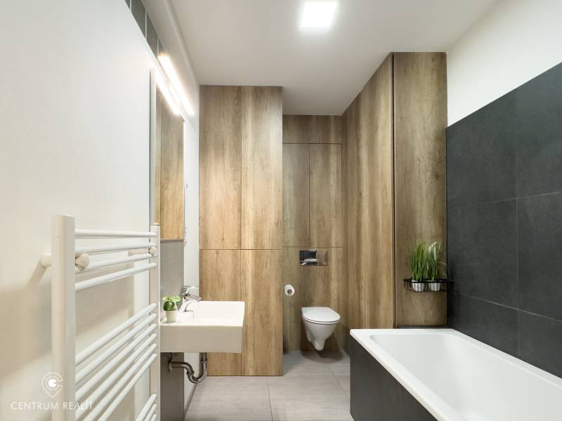 A bathroom in a 3-room apartment with a bathtub, a sink, and walls with a wooden decor.