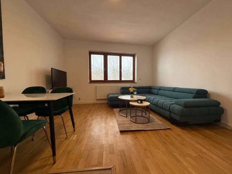 Living room in a family house with a green sofa, dining table, and wooden decor flooring.