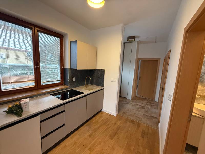 A kitchen in a family house with a wood-patterned floor, white cabinets, and a large window.