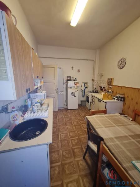 A kitchen in a family house with a wooden decor floor, a table, and kitchen cabinets.