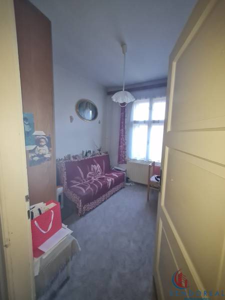 A room in a family house with a sofa, carpet, and curtains on the windows.
