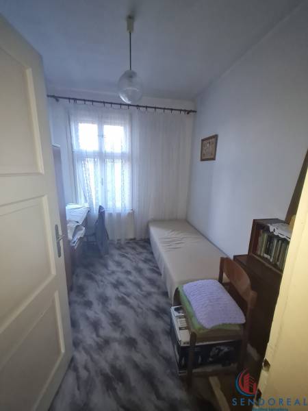 Cozy bedroom in a family house with a wood-decor floor and simple furniture.