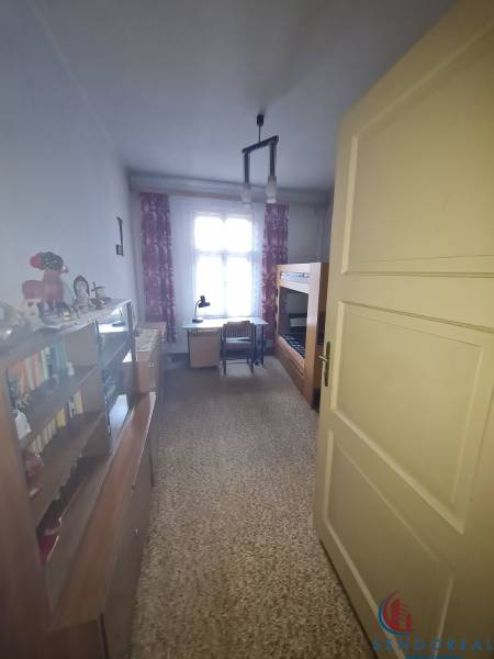 A room in a family house with a bed, a desk, a wardrobe, and decorations on the shelf.