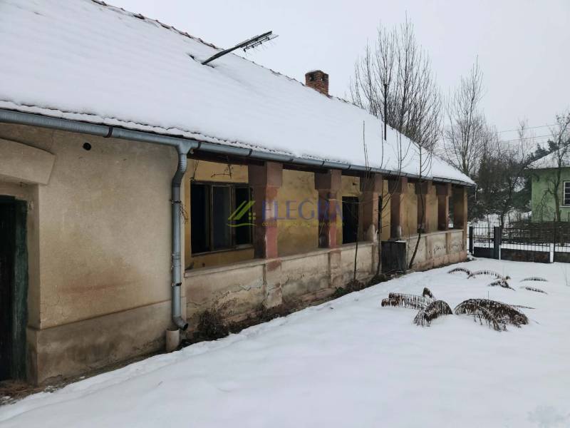A family house in Felsőtelekes with a snow-covered roof and an old facade in the winter season.