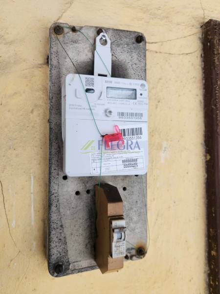 There is an electric meter with a seal placed on the wall in the family house.