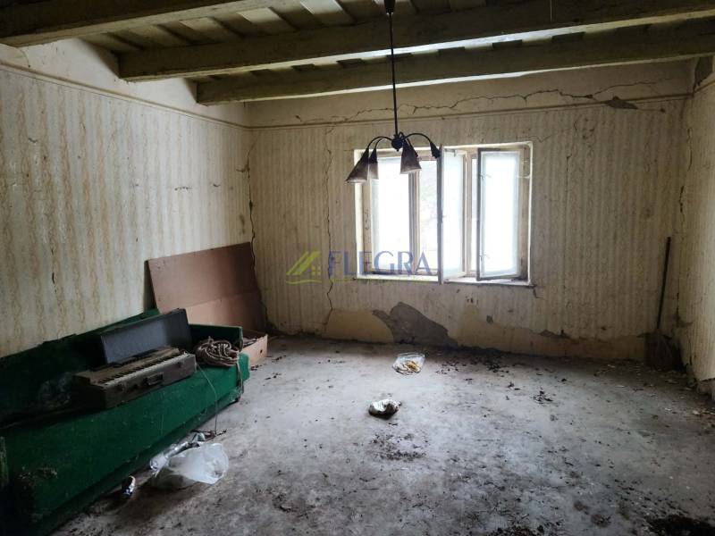 An abandoned room with cracked walls and a broken window in a family house.