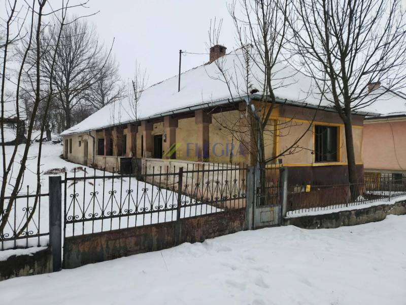 A family house in Felsőtelekes surrounded by a blanket of snow and trees.