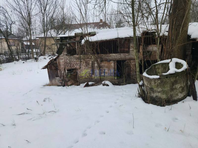 A snowy yard in Felsőtelekes with a dilapidated building next to an old concrete structure.