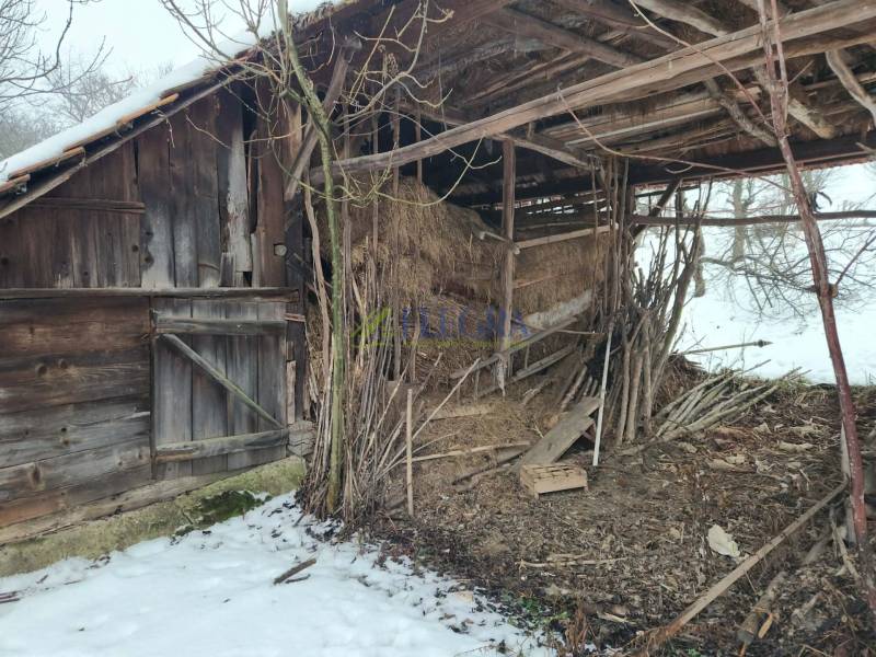 A wooden structure at a family house in Felsőtelekes, covered with snow and trees.