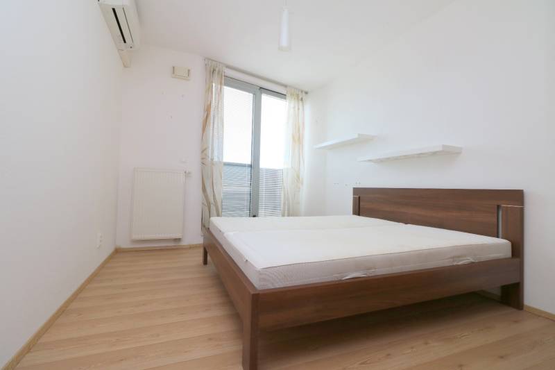 A bedroom with a bed, shelves, and a wooden decor floor in a two-room apartment.