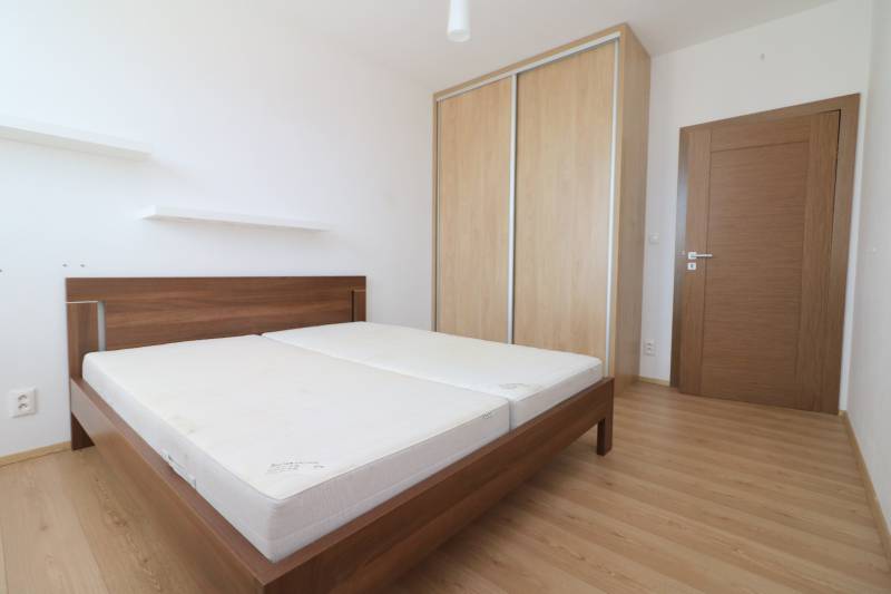 Bedroom in a 2-room apartment with a bed, wardrobe, and floor with wooden decor.