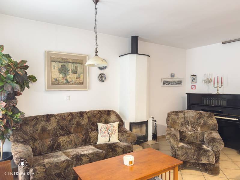 Living room in a family house with a sofa, fireplace, piano, and wall decorations.