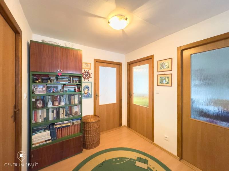 Interior of a family house with a bookshelf, wooden doors, and a floor with a wood decor.