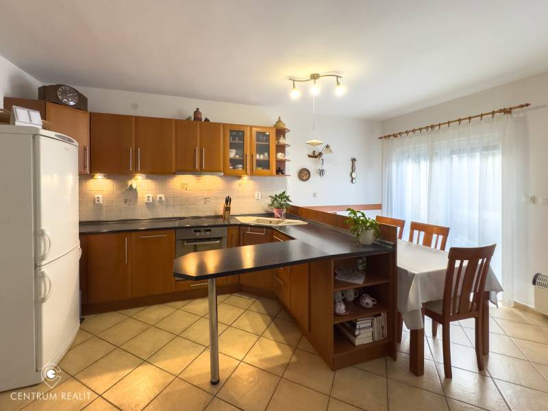 A kitchen in a family house with tiles, a dark counter, and a dining table.