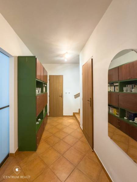 A hallway in a family house with tiles, a mirror, and wooden doors.