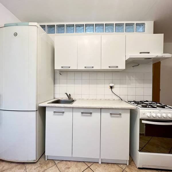 A kitchen with white cabinets and a refrigerator in a studio apartment.