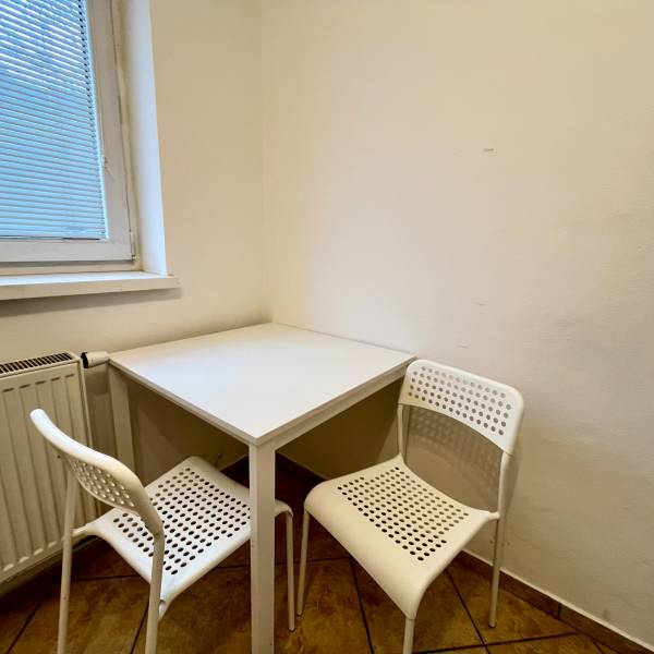 A small dining nook with a white table and two chairs in a studio apartment.