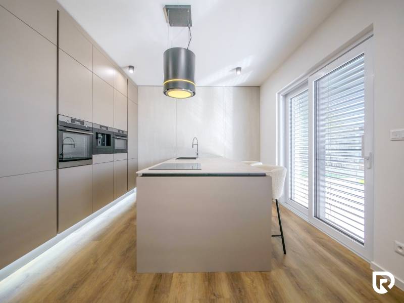 A kitchen in a family house with an island, built-in appliances, and a wooden decor floor.