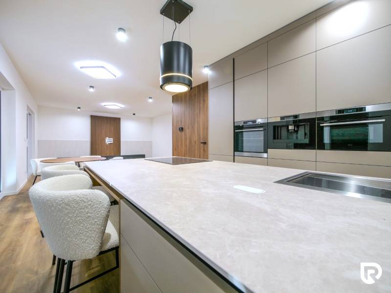 A kitchen in a family house with a wooden decor floor and built-in appliances.