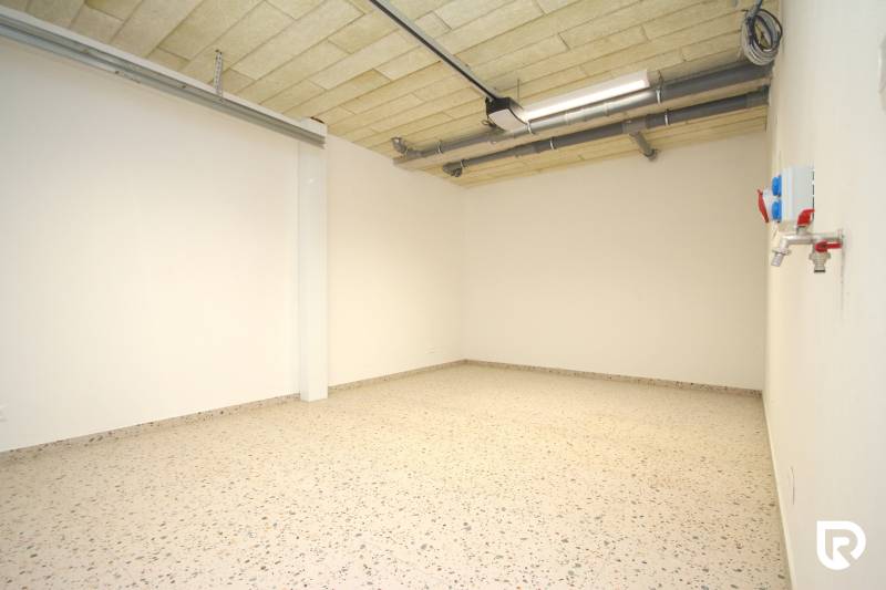 Family house with a concrete floor and ceiling pipes, white walls.