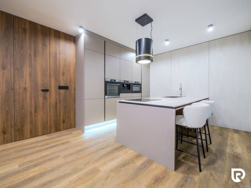 A kitchen in a family house with an island and a floor with a wooden decor.