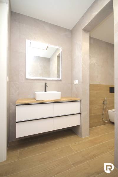 A bathroom in a family house with a wooden decor floor and a sink on a cabinet.