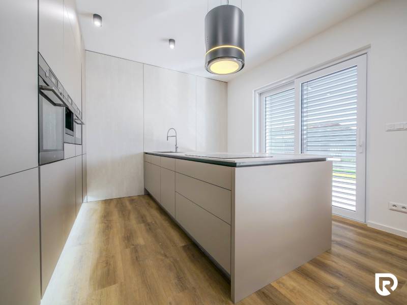 A kitchen in a family house with a wood-patterned floor and built-in appliances.