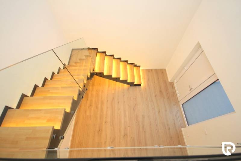 Glass staircase with backlighting and wood-patterned flooring in a family house.