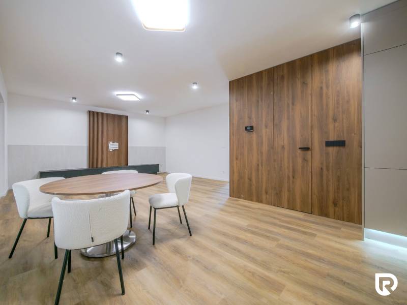 Dining table with white chairs and a wall with wooden decor in a family house.