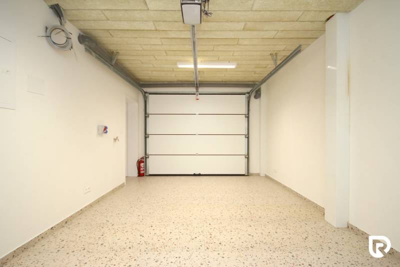 A spacious garage with white walls and floor in a family house.