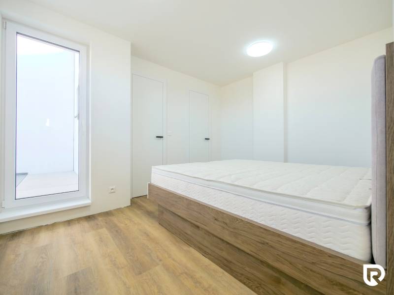 A bright bedroom with a bed and wood-decorated flooring in a family house.