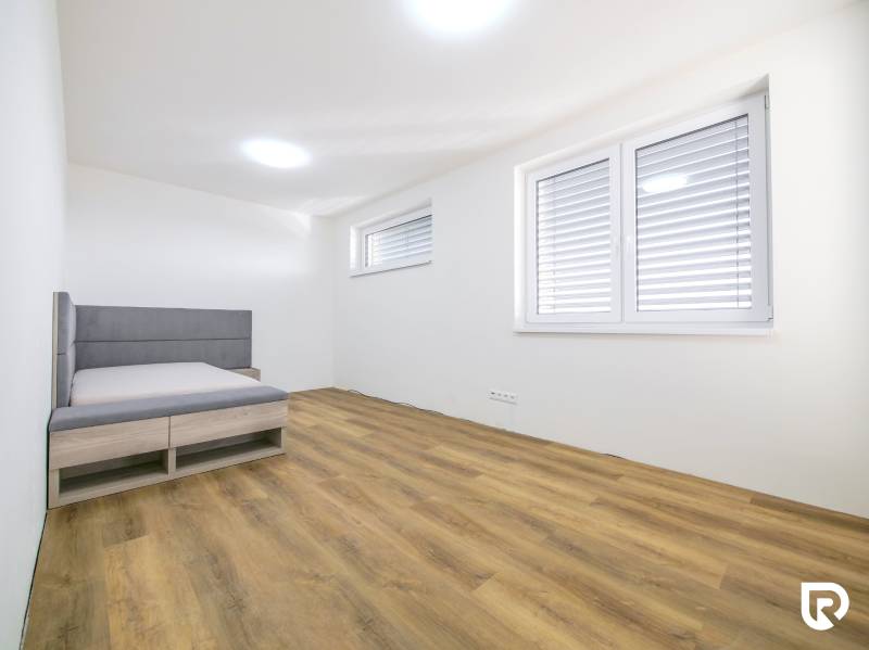 A simply furnished room in a family house with a bed and a wooden decor floor.