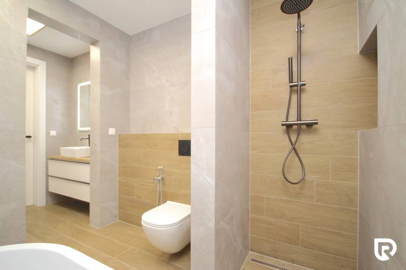 A bathroom in a family house with a wooden decor floor and a shower corner.