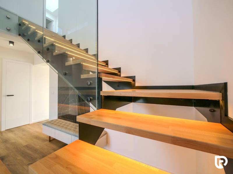 Modern staircase with wooden decor and glass railing in a family house.
